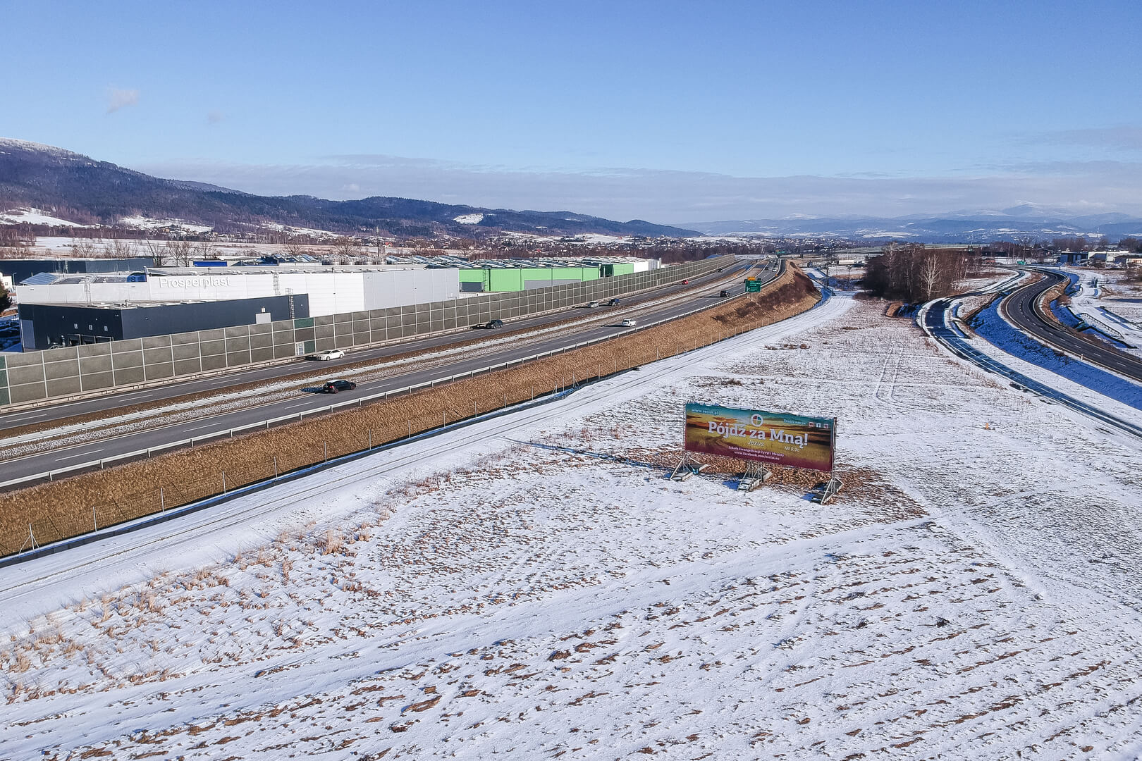 Ujęcie z drona prezentujące billboard w zimowej scenerii.